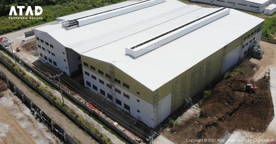 Een groot kantoorgebouw met een voorgewerkt staalconstructie met een scheef dak en betonnen fundering